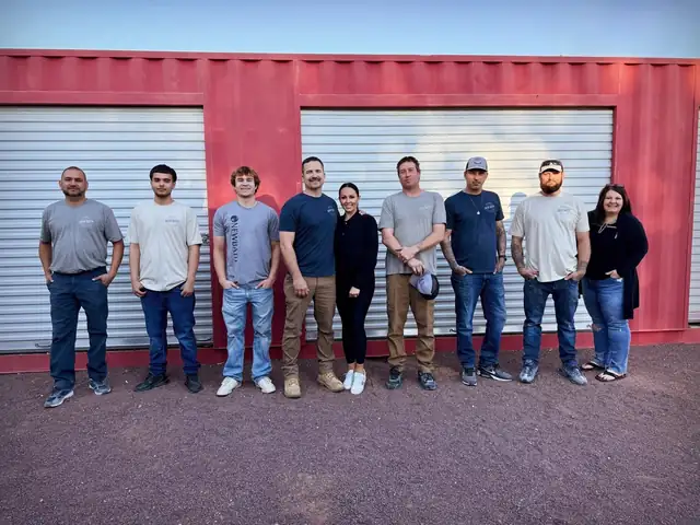 The AZ New Bath team standing together outdoors in front of a red storage container