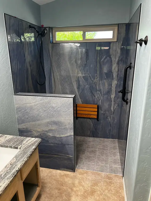 Walk-in shower with blue stone-look panels, teak fold-down seat, grab bar and clerestory window