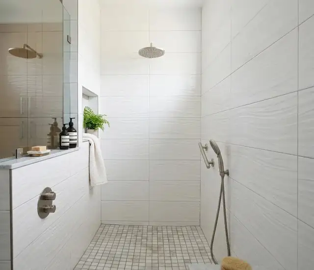 Curbless walk-in shower with white wave-texture wall tile, mosaic floor and brushed nickel rain head