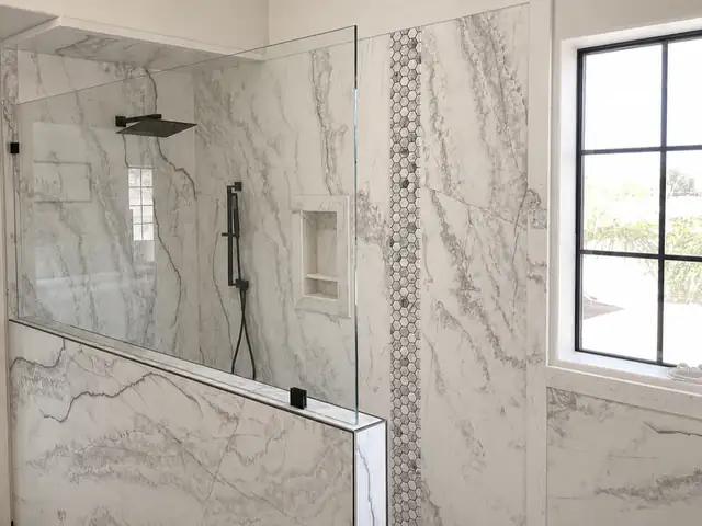 Shower remodel with white marble-look porcelain walls, a hex mosaic accent stripe, niche and matte black rain head
